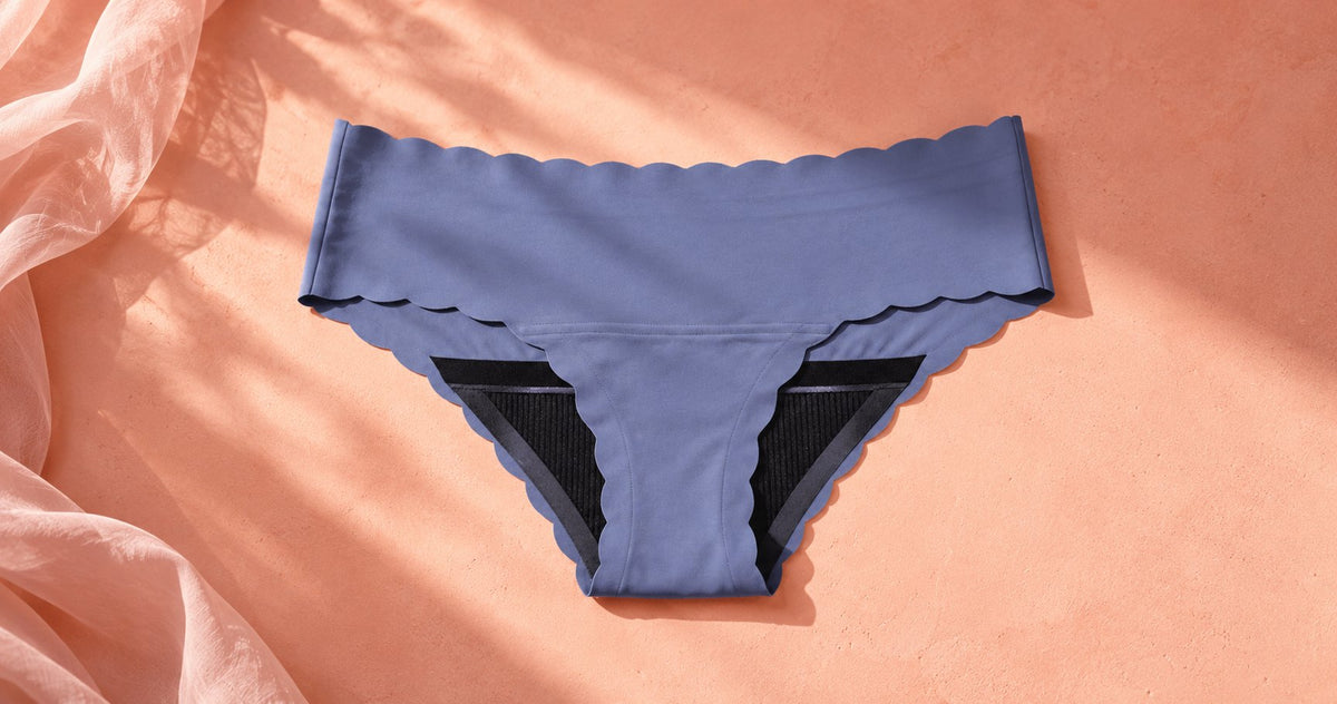 Blue scalloped seamless period underwear laid flat on a peach surface